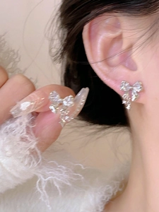 Detail of silver bow tassel earrings with sparkling crystals worn by a fashion model