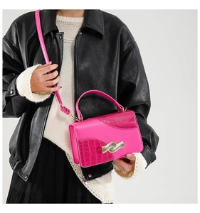 Detail of bright pink PU leather shoulder bag with gold wave buckle and croc embossing