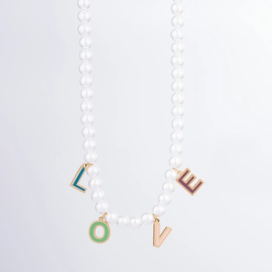 Detail of beaded necklace featuring white pearls and colorful LOVE enamel pendants