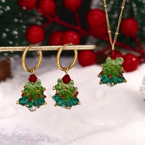 Detailed view of handmade crystal Christmas tree earrings and necklace with gold accents