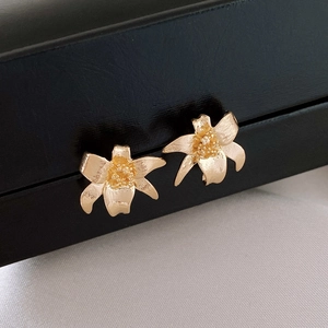 Boucles d'oreilles fleurs dorées au fini métallique sur une boîte noire