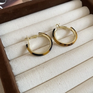 Macro shot of gold-plated resin hoops with tortoiseshell pattern in velvet jewelry box