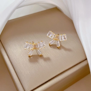 Close-up of golden bow earrings set with sparkling rectangular crystals on jewelry box