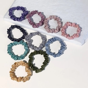 Set of minimalist satin silk hair scrunchies in assorted colors on marble base