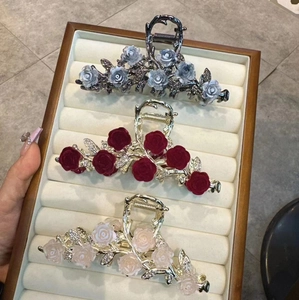 Elegant metal rose shark hair clips with tassel and velvet floral designs on wood tray