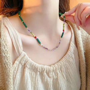 Close-up of handmade shell necklace with green malachite texture beads and gold spacers