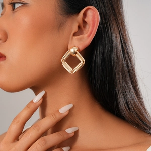 Gros plan de boucles d'oreilles losanges géométriques dorées sur un mannequin