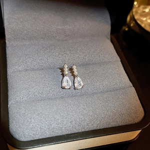 Gros plan de boucles d'oreilles gouttes en zircon et perles sur un écrin en velours