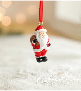Close-up of hand-painted resin Santa ornament with red ribbon and holiday branding