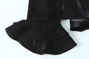 Detail shot of black glossy fabric with layered ruffle design on a fashion shirt