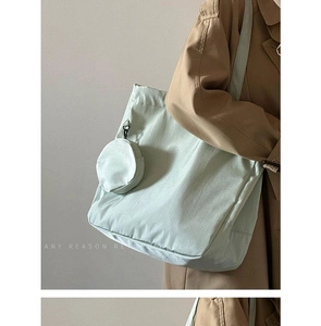 Detail of mint green nylon tote bag with matching coin purse on a stylish trench coat