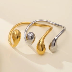 Dettaglio di bracciali aperti a goccia d'oro e d'argento con finitura a specchio lucida