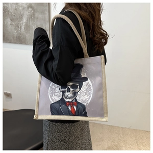 Gothic skull canvas tote bag with beige woven edges shown on model's shoulder