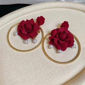 Detailed macro of red velvet rose earrings with pearls and gold hoop texture
