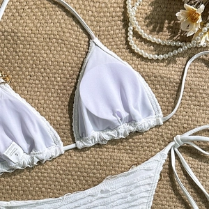 Flat lay of white textured bikini set with metallic details and shell-patterned fabric