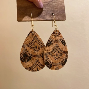 Detail of bohemian teardrop cork earrings featuring black ethnic mandala patterns on gold hooks