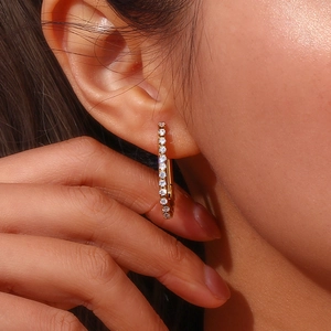 Macro detail of 18K gold plated U-shaped hoop earrings with sparkling zircon inlay