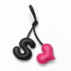 Handmade leather S-letter and pink heart bag charm with black cord on white background