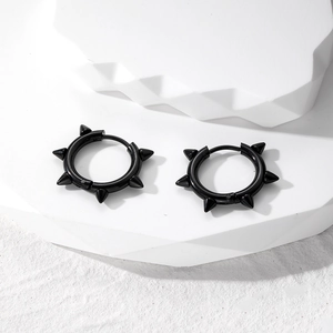 Close-up of black punk rivet huggie earrings with five cone spikes on stone