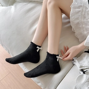 Close-up of black cotton ankle socks with white bow detail and lace bubble cuffs