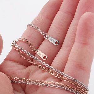 Macro detail of silver and rose gold stainless steel chains with S.STEEL engraved tags