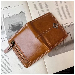 Detail of brown faux leather card holder with white stitching and silver cross emblem