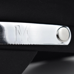 Macro shot of silver metal M logo and rivet detail on black fabric beret hat