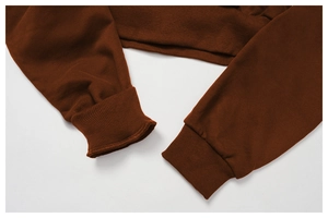 Detail shot of ribbed cuffs and hem on dark brown fleece hoodie with textured cotton fabric