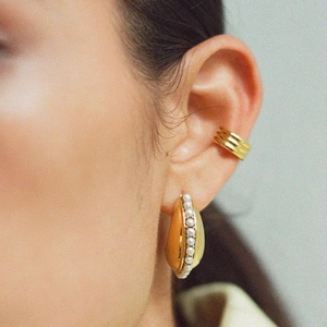 Macro view of gold plated stainless steel pearl earring and triple ear cuff on model