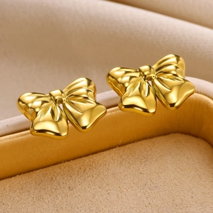 Detailed macro view of 18K gold bow stud earrings with a matte textured metallic finish