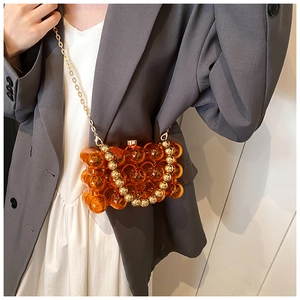 Close-up of amber acrylic bubble bag with golden chain strap and pearl handle detail