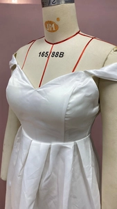 Detail of the white strapless V-neck satin dress showing the pleated skirt and waistline