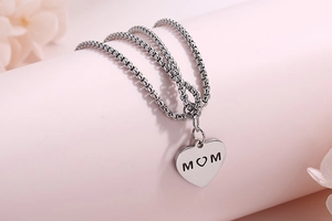 Detail of silver dual-layer chain bracelet featuring heart charm with MOM engraving