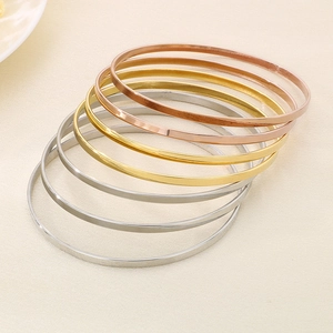 Detail view of stacked minimalist titanium steel bangles in rose gold, gold, and silver