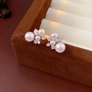 Close-up of floral pearl earrings with clear crystals on a brown jewelry box