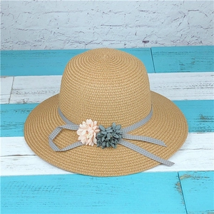 Detail of woven straw sun hat with grey polka dot ribbon and fabric flower accents