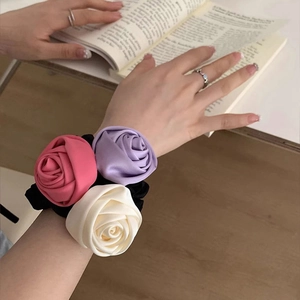 Detail of pink, purple, and cream fabric roses on a black satin hair scrunchie wristlet