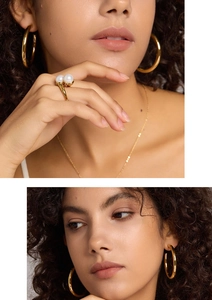Detailed view of elegant gold pearl ring and matching chunky hoop earrings on model