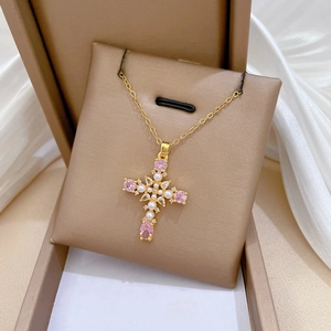 Detail of gold cross necklace with pink gemstones and white pearls on silk background