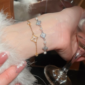 Detailed close-up of elegant gold and silver four-leaf clover bracelets with pearls on wrist