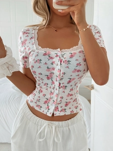 Detail of white Y2K cropped T-shirt featuring floral print, lace trim, and button front