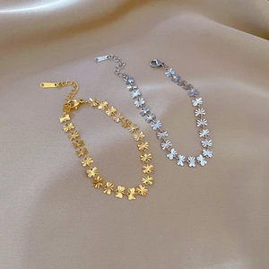 Minimalist titanium steel bracelet featuring frosted floral clover links on champagne silk