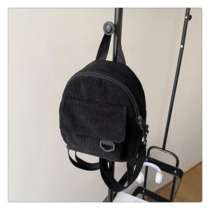 Detail of vintage black corduroy mini backpack texture with front pocket and D-ring buckle