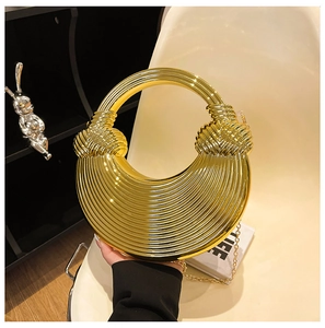 Detail der goldenen Metall-Halbmondtasche mit horizontalen Streifen und Kettenriemen