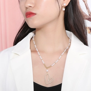 Gros plan d'un collier de perles avec pendentif cœur et boucles d'oreilles assorties