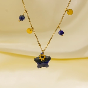 Detail of gold necklace featuring blue star stone pendant on luxury silk background
