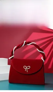 Detail of red velvet handbag with pearl handle and golden bow clasp for weddings