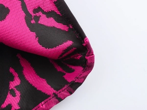Close-up detail of rose red and black jacquard fabric with fine stitching and textures