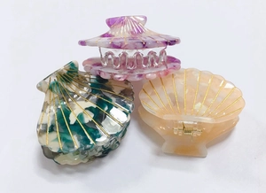 Detailed view of three shell-shaped acetate hair claws with elegant marble patterns