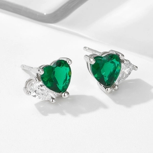Macro detail of emerald heart-shaped zircon earrings with silver setting and drop stones